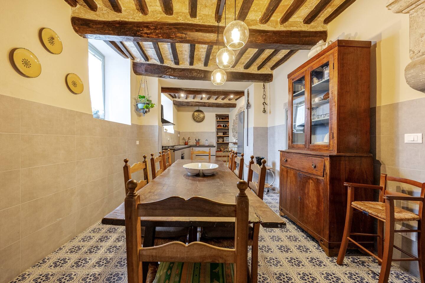 Cucina del piano terra con lungo tavolo da pranzo e zona cottura sullo sfondo