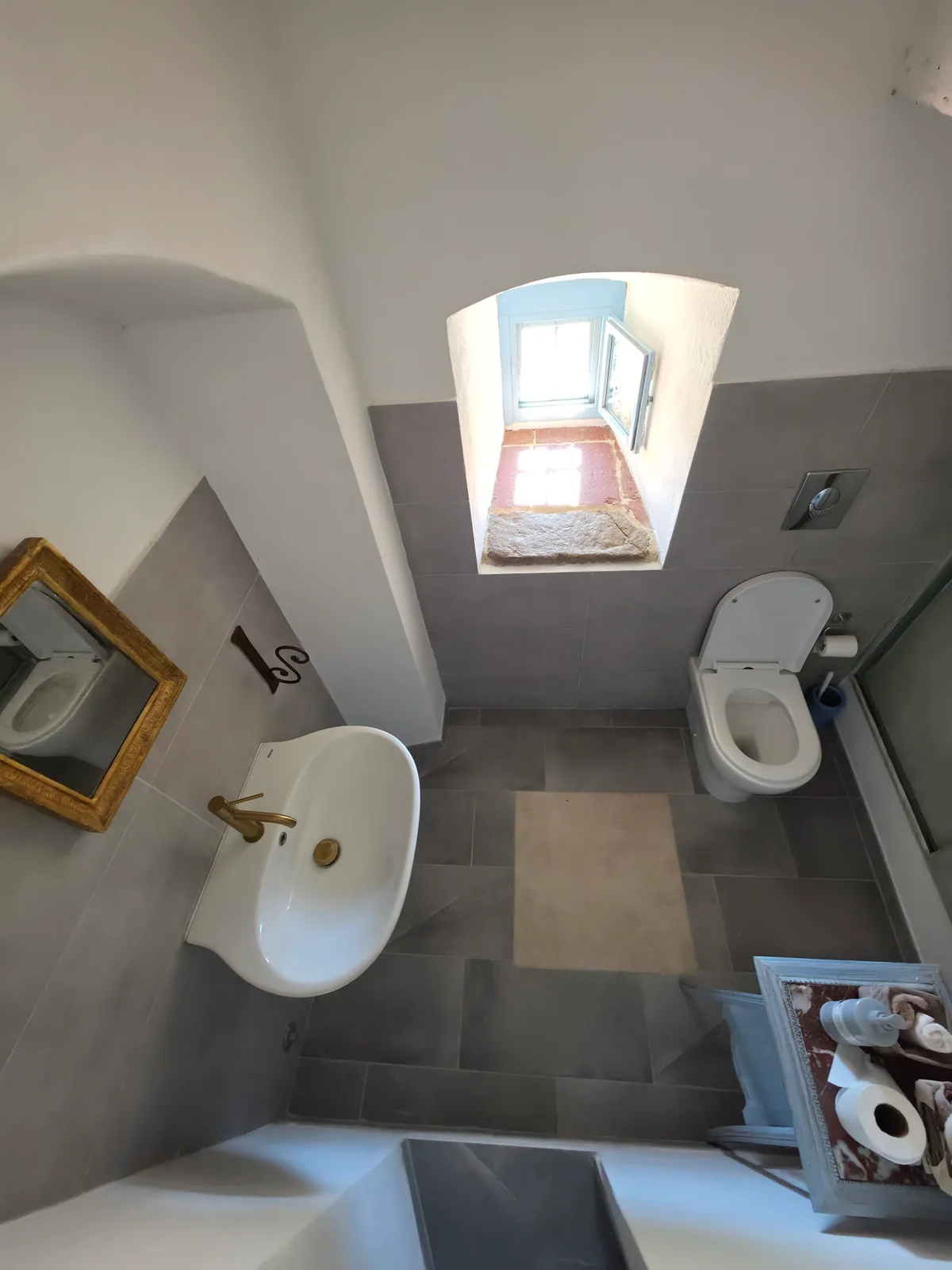 Vista d’insieme della toilette al piano terra, con lavabo, WC e finestra nella parete spessa